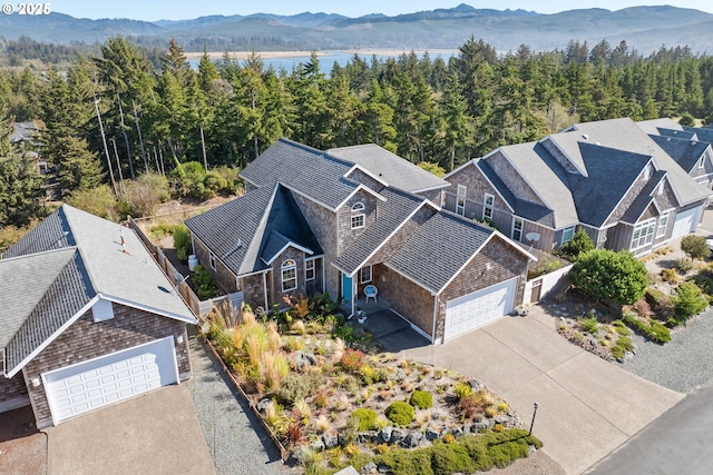 drone / aerial view with a forest view and a water and mountain view