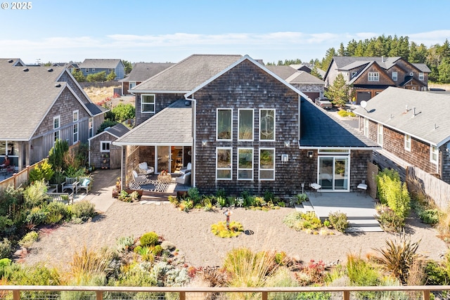 back of property with a fenced backyard, a residential view, roof with shingles, and a patio