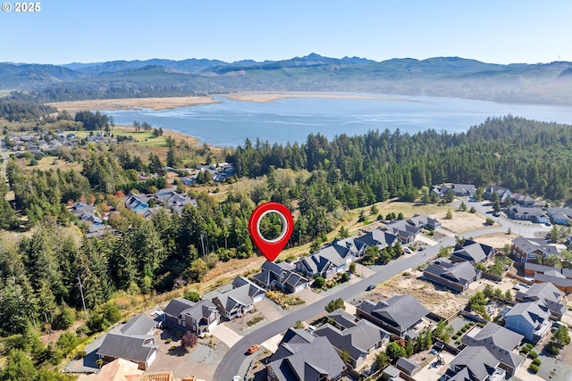birds eye view of property featuring a residential view, a water and mountain view, and a forest view
