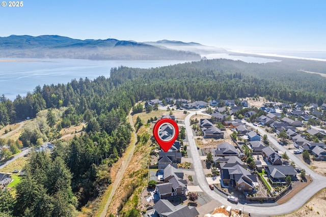 birds eye view of property with a water and mountain view and a wooded view