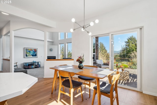 dining area with arched walkways, baseboards, and light wood-style floors
