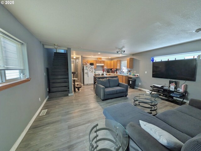 1912 SE 122nd Ave Unit 11, Portland, OR 97233 - living room with stairway, baseboards, light wood-style flooring, and a textured ceiling