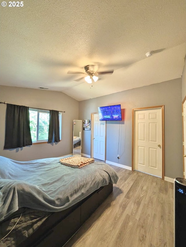 1912 SE 122nd Ave Unit 11, Portland, OR 97233 - bedroom with vaulted ceiling, light wood-style flooring, a textured ceiling, ceiling fan, and baseboards