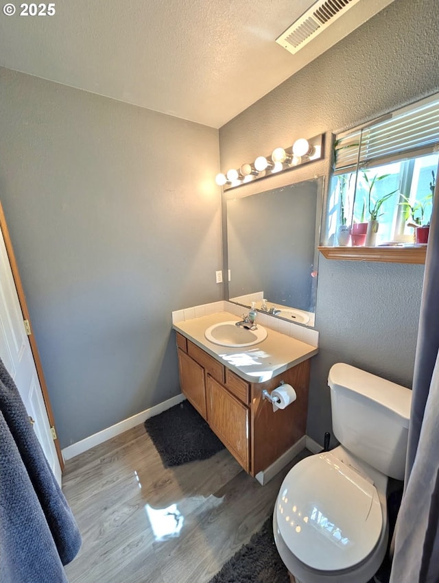 1912 SE 122nd Ave Unit 11, Portland, OR 97233 - half bathroom with wood finished floors, vanity, toilet, baseboards, and a textured ceiling
