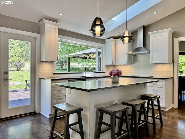 24035 SW Mountain Creek Rd, Sherwood, OR 97140 - kitchen featuring wall chimney range hood, healthy amount of natural light, a kitchen breakfast bar, dark wood-type flooring, and recessed lighting