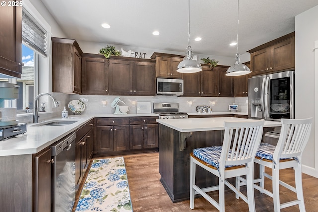 52152 Casswell Dr, Scappoose, OR 97056 - kitchen featuring stainless steel appliances, dark brown cabinets, a kitchen bar, light countertops, and decorative backsplash