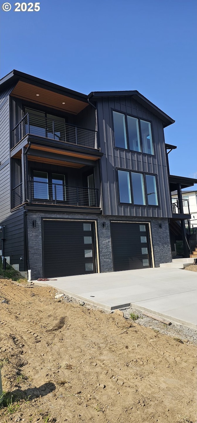 243 NE Hemmingway Dr, Stevenson, WA 98648 - contemporary house with an attached garage, a balcony, concrete driveway, and board and batten siding
