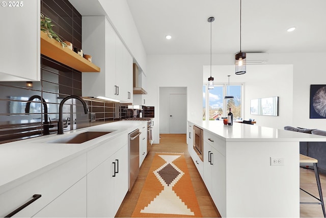 kitchen with white cabinets, sink, decorative light fixtures, a kitchen island, and stainless steel appliances