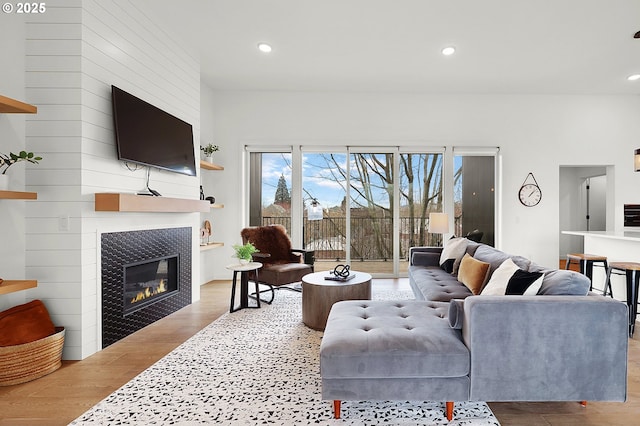 living room featuring a tile fireplace, plenty of natural light, and light hardwood / wood-style floors