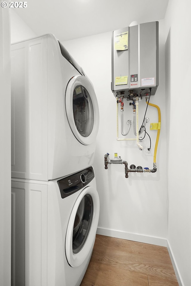 laundry room featuring stacked washer and dryer, tankless water heater, and light wood-type flooring