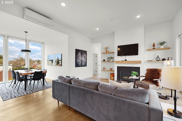 living room with light hardwood / wood-style floors, a fireplace, and a wall mounted AC