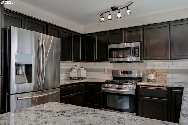 kitchen with light stone counters, backsplash, and stainless steel appliances