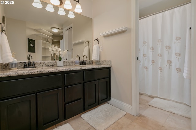 full bath with double vanity, baseboards, a sink, and tile patterned flooring