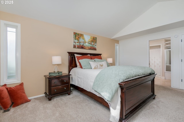 bedroom with baseboards, light carpet, connected bathroom, and lofted ceiling