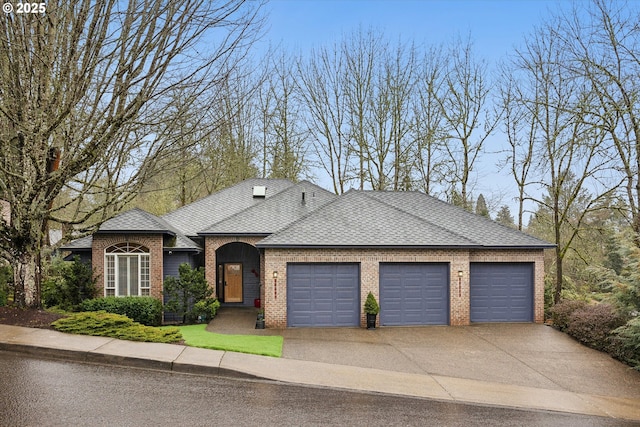 view of front of property featuring a shingled roof, concrete driveway, brick siding, and an attached garage