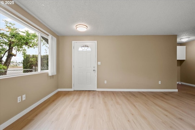 entryway featuring light wood finished floors, a textured ceiling, and baseboards