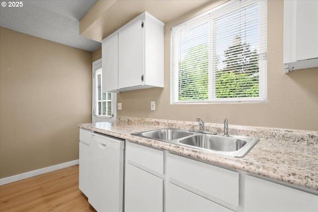 kitchen with dishwasher, a sink, light countertops, and white cabinetry