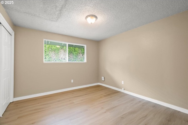 unfurnished bedroom with light wood-style floors, a closet, a textured ceiling, and baseboards