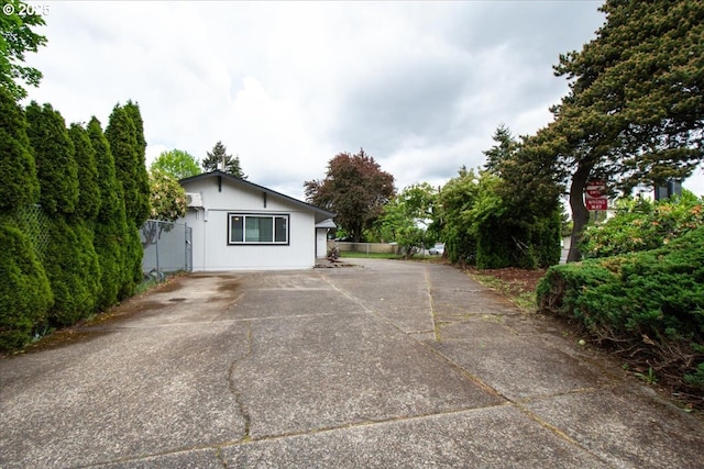 view of side of home featuring concrete driveway and fence