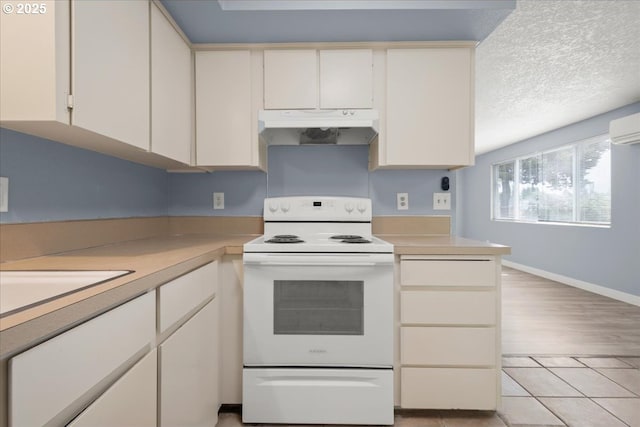 kitchen featuring under cabinet range hood, white range with electric stovetop, light countertops, and baseboards