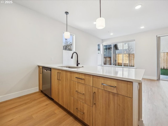 kitchen featuring sink, light hardwood / wood-style flooring, dishwasher, hanging light fixtures, and kitchen peninsula