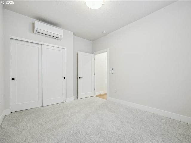 unfurnished bedroom with light carpet, a wall unit AC, a closet, and a textured ceiling