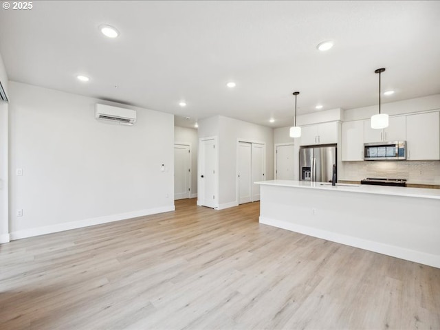 kitchen with stainless steel appliances, white cabinets, light hardwood / wood-style floors, and decorative light fixtures