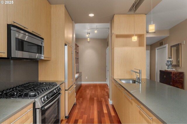 kitchen featuring stainless steel appliances, a sink, light brown cabinets, modern cabinets, and light wood-type flooring