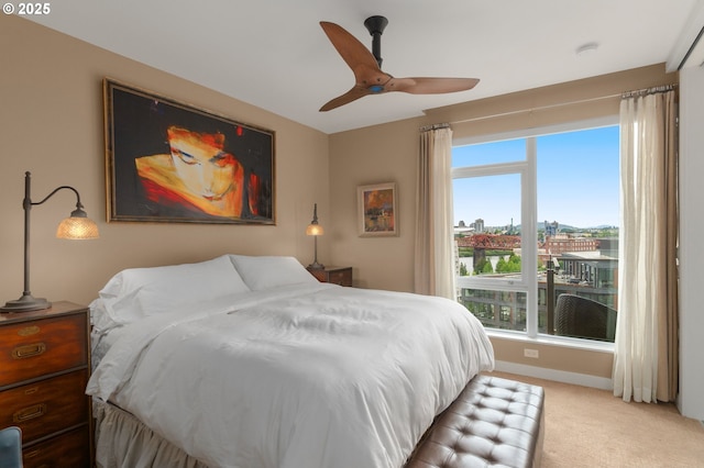 bedroom featuring light carpet, multiple windows, baseboards, and a ceiling fan
