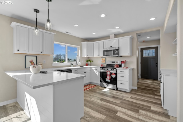 313 Art Kegler Blvd, Boardman, OR 97818 - kitchen with appliances with stainless steel finishes, a peninsula, white cabinetry, light wood-type flooring, and light countertops