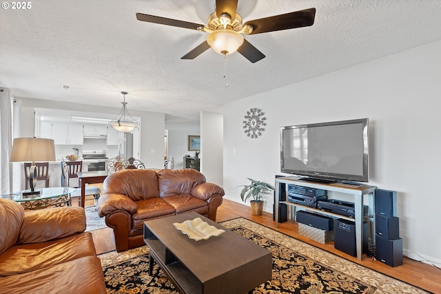 living room with hardwood / wood-style flooring, ceiling fan, and a textured ceiling