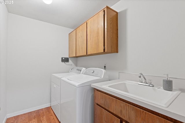 laundry area with separate washer and dryer, sink, cabinets, and light wood-type flooring