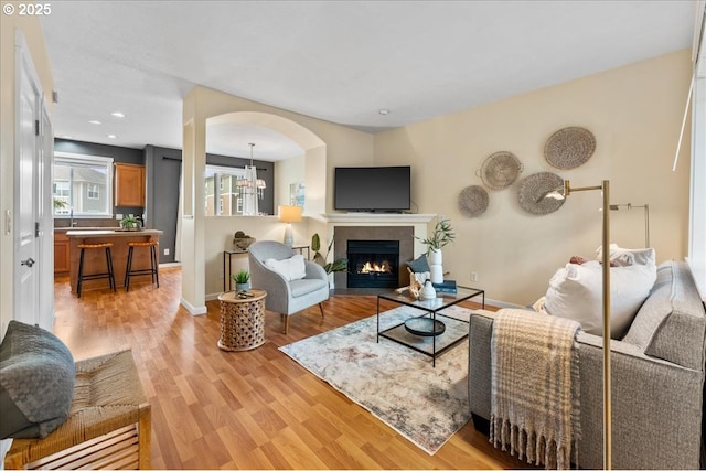 living room with a tile fireplace and light wood-type flooring