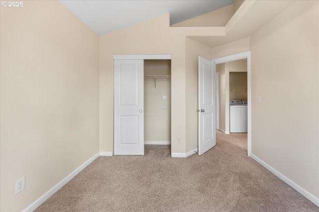 unfurnished bedroom with light carpet, washer / dryer, vaulted ceiling, and a closet