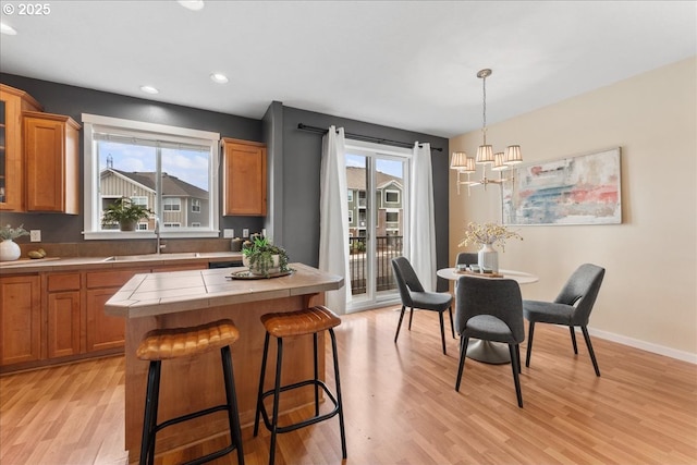 kitchen with a healthy amount of sunlight, sink, light wood-type flooring, and decorative light fixtures