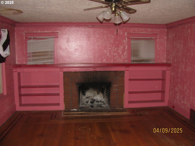 unfurnished living room featuring a textured ceiling, wood finished floors, ceiling fan, and a fireplace