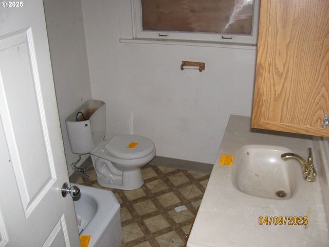 bathroom featuring toilet, tile patterned floors, a sink, and baseboards