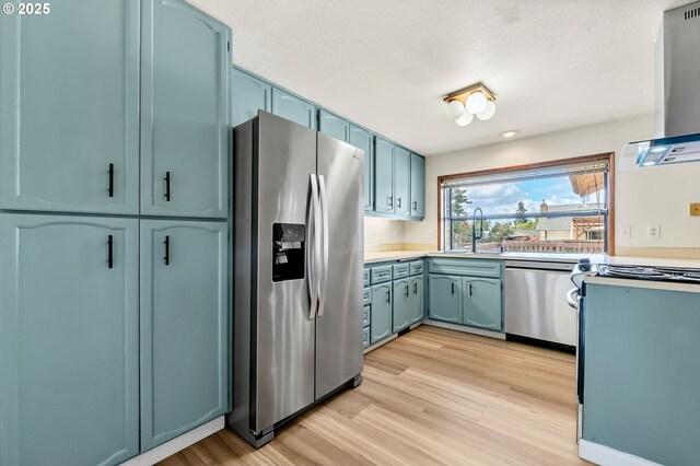 590 Granite Pl, Springfield, OR 97477 - kitchen featuring appliances with stainless steel finishes, light wood-type flooring, light countertops, blue cabinetry, and island exhaust hood