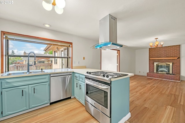 590 Granite Pl, Springfield, OR 97477 - kitchen featuring appliances with stainless steel finishes, island range hood, a chandelier, a peninsula, and light wood-style flooring