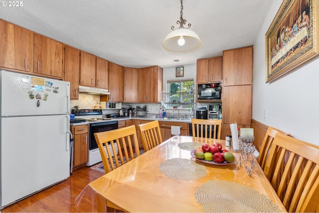 2710 SE 138th Ave Unit 48, Portland, OR 97236 - kitchen featuring freestanding refrigerator, range with electric cooktop, black microwave, under cabinet range hood, and brown cabinets