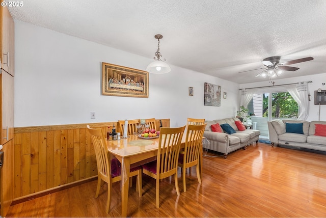 2710 SE 138th Ave Unit 48, Portland, OR 97236 - dining area with wood finished floors, a textured ceiling, wainscoting, a ceiling fan, and wood walls