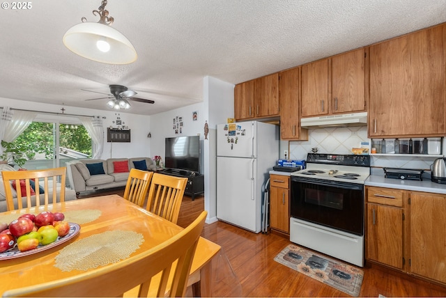 2710 SE 138th Ave Unit 48, Portland, OR 97236 - kitchen with electric range oven, freestanding refrigerator, under cabinet range hood, light countertops, and brown cabinets
