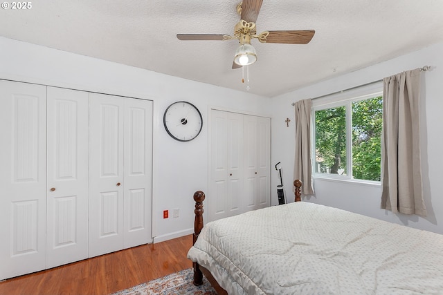 2710 SE 138th Ave Unit 48, Portland, OR 97236 - bedroom featuring two closets, wood finished floors, a textured ceiling, baseboards, and a ceiling fan