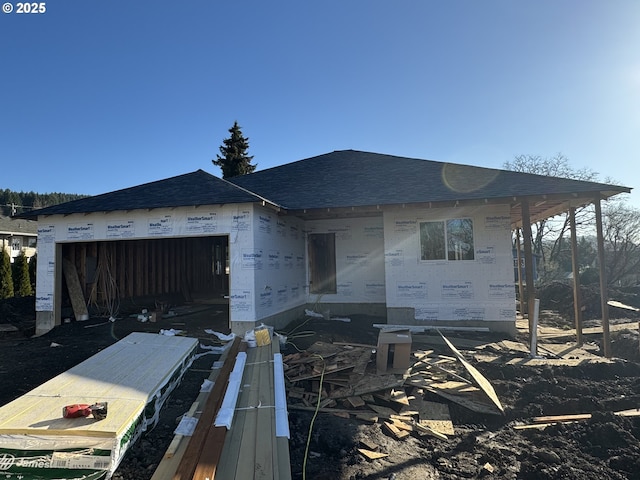 unfinished property with an attached garage and roof with shingles