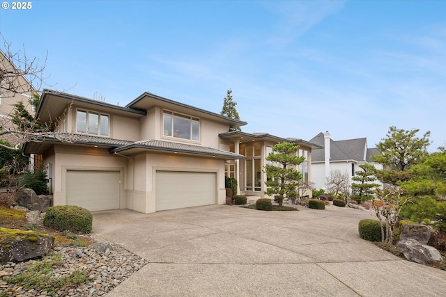 prairie-style home featuring driveway, an attached garage, a tiled roof, and stucco siding