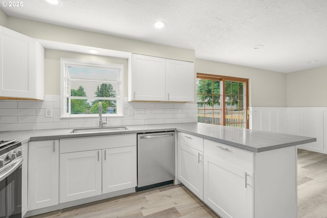 14108 NE 49th St, Vancouver, WA 98682 - kitchen featuring appliances with stainless steel finishes, a sink, a peninsula, white cabinetry, and light wood-style floors