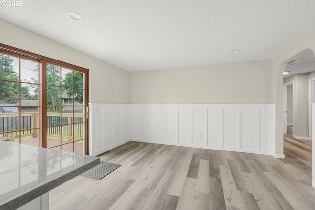 14108 NE 49th St, Vancouver, WA 98682 - spare room featuring arched walkways, light wood finished floors, a wainscoted wall, a decorative wall, and a textured ceiling