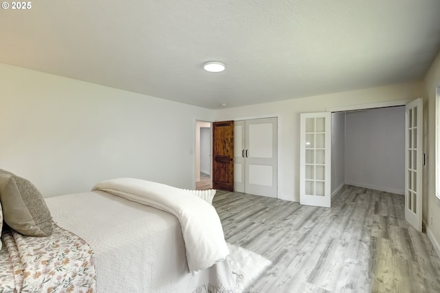 bedroom with french doors, light wood-style floors, and baseboards