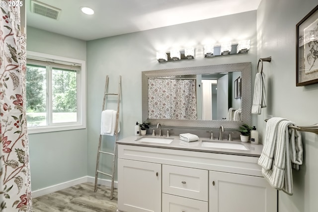 full bath featuring wood finished floors, double vanity, baseboards, recessed lighting, and a shower with curtain