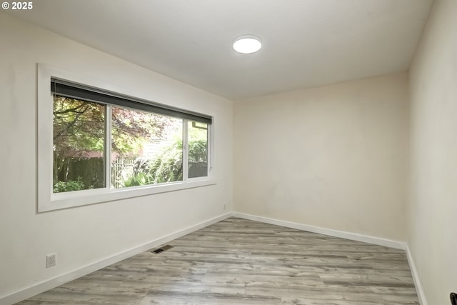 spare room with baseboards and wood finished floors